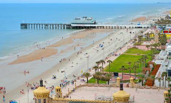 An aerial view of the wide Daytona Beach coastline and the Daytona Beach Pier and Oceanfront Bandshell